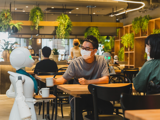 The Innovation Cafe Tokyo. A restaurant robot serves a table of customers. 