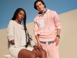 Photograph of a young black woman with braids in a wheelchair, standing next to a man in pink sportswear